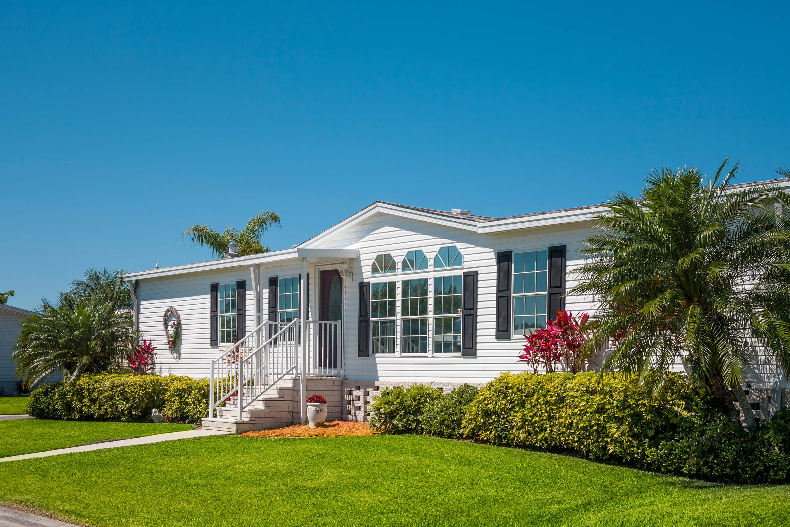 Well-maintained mobile home with tropical landscaping, representing the importance of reliable manufactured homes insurance coverage for Florida homeowners