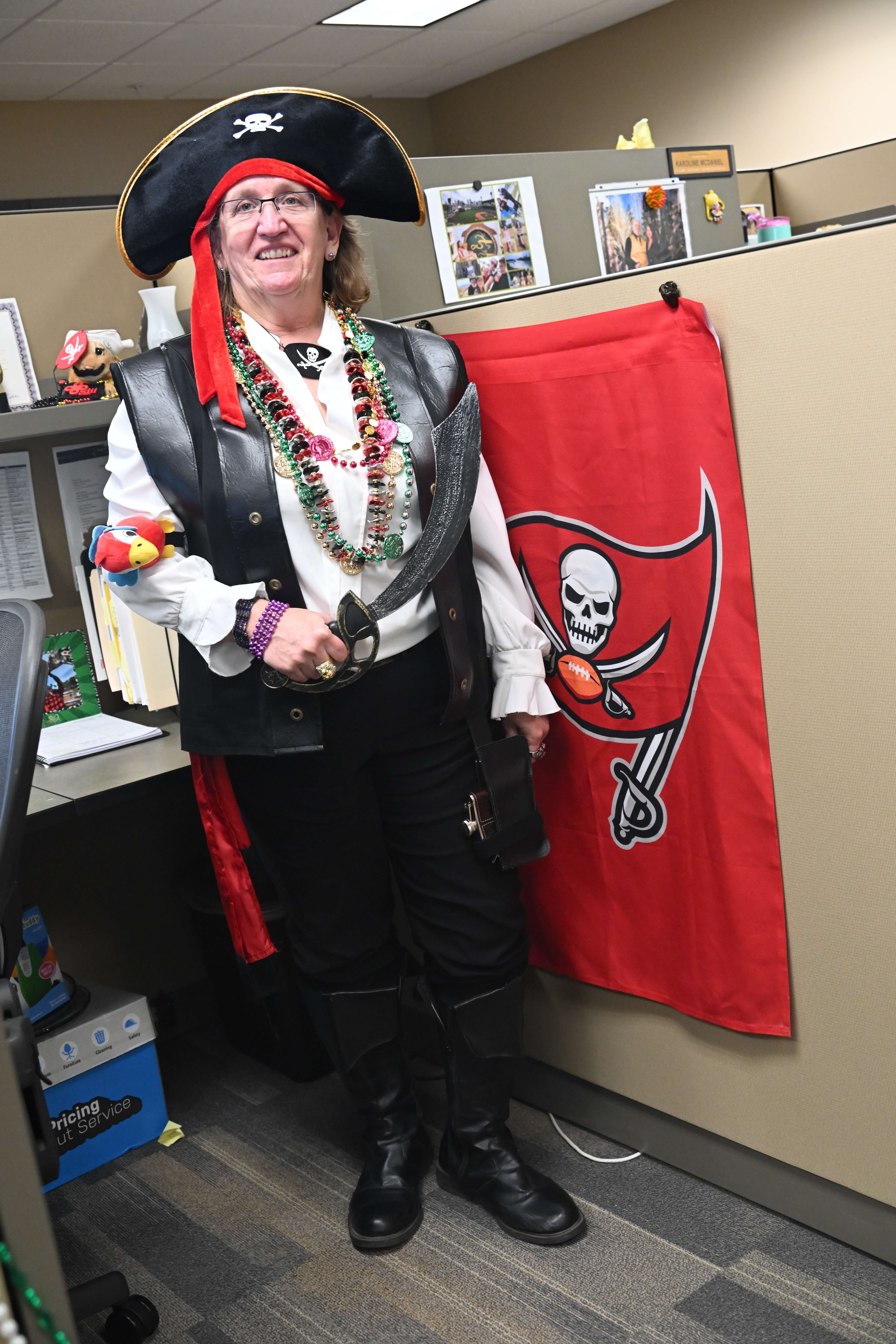 Another claims team member dressed up like a pirate in front of a Tampa Bay Buccaneers flag